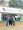 Um grupo de quatro pessoas, três homens e uma mulher, está de pé e sorrindo em frente a um grande banner de entrada do evento. O banner diz "AVISTAR 2024 - Encontro Brasileiro de Observação de Aves" e mostra imagens de pássaros. O evento acontece nos dias 17, 18 e 19 de maio em São Paulo, SP. O grupo parece ser parte da equipe do Parque das Aves, com alguns membros vestindo camisetas com o logotipo do parque. A área de entrada está movimentada, e há placas indicando várias áreas do evento, como workshops, palestras e alimentação.