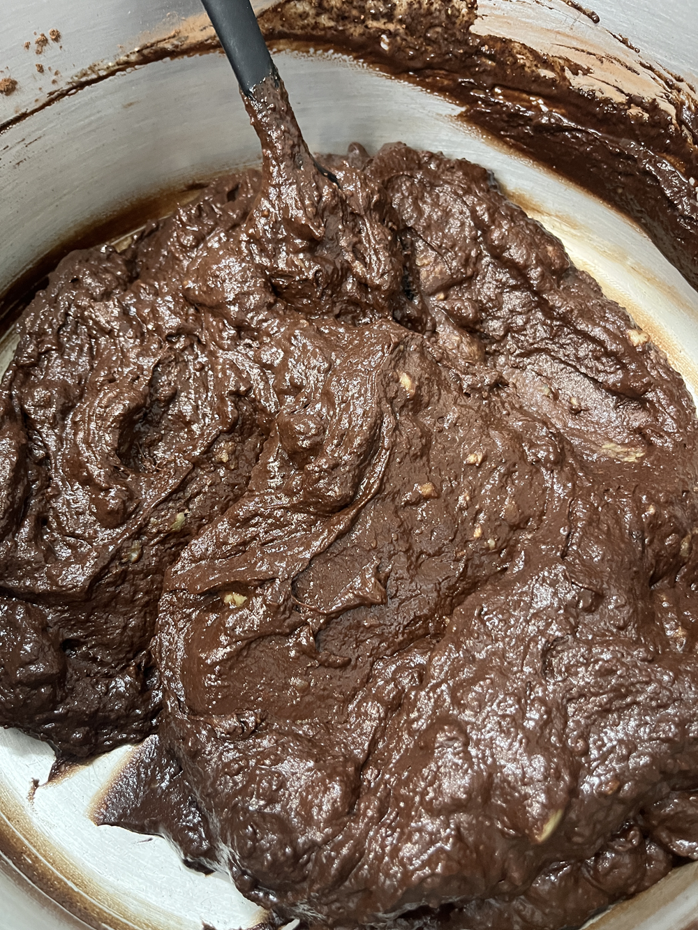 Mistura de ingredientes do brigadeiro vegano, com uma espátula dentro de uma panela, mostrando a consistência cremosa da massa de chocolate.